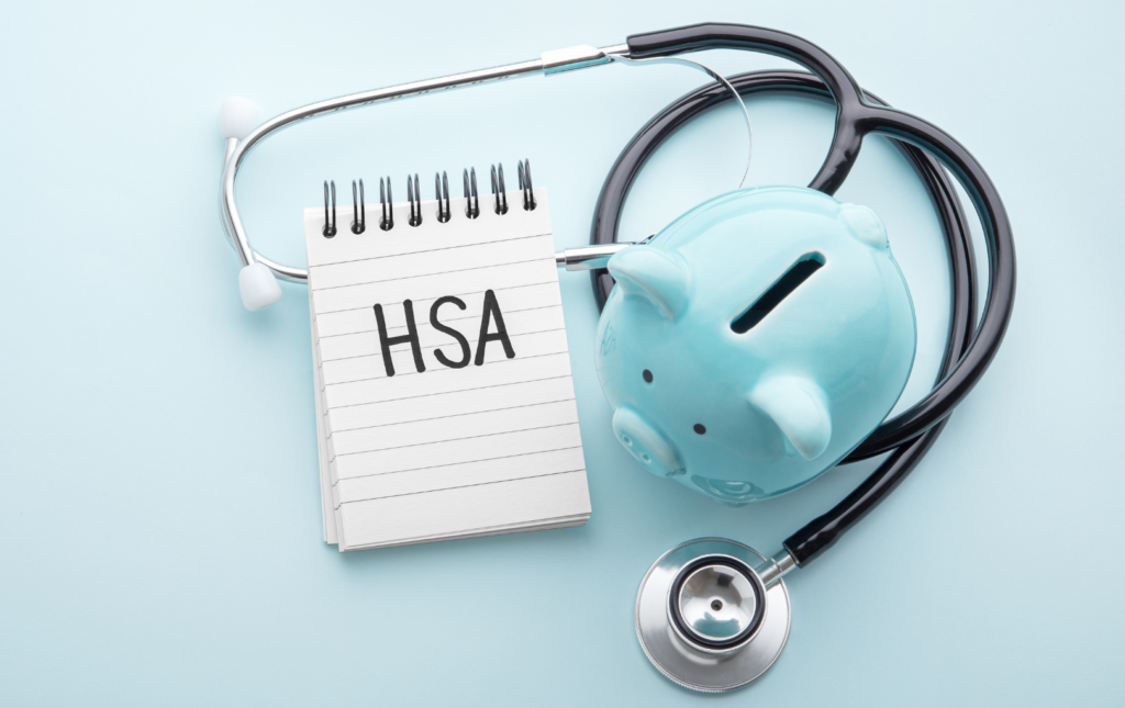 A Piggy Bank With A Stethoscope around it alongside a pad that says HSA on it. HSA stands for health savings account and why I love them and what you need to know about them
