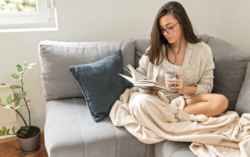 Woman on a couch reading to increase her financial literacy and empower herself to overcome financial challenges of women