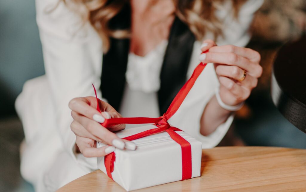 A woman that is opening a gift box with a gift for the person that has everything