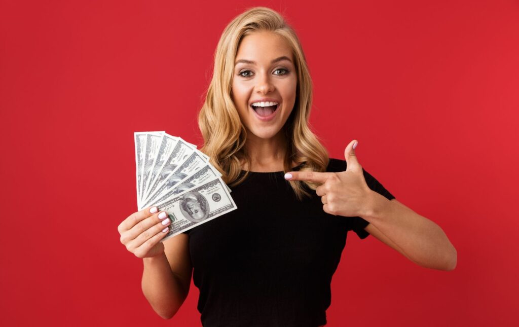 A happy young woman holding cash in one hand; she is grateful for the ability to get the gift of financial advice and a plan