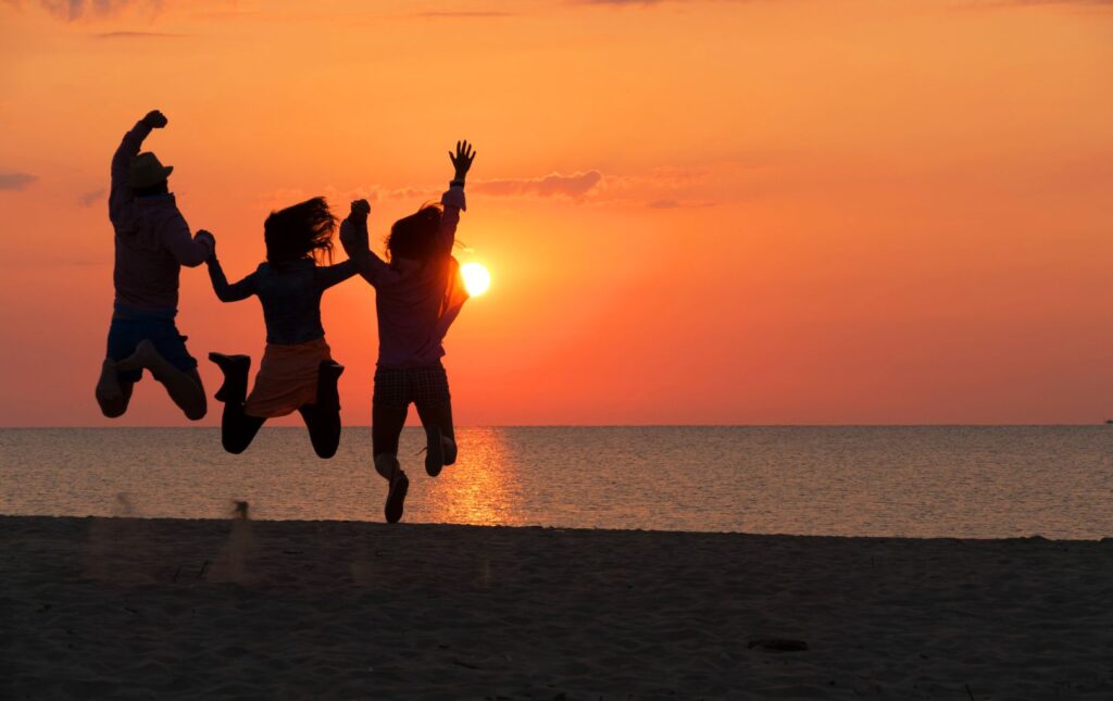 Three people jumping up in celebration of the benefits of saving for college with just their shadows visible in front of the sunset.  