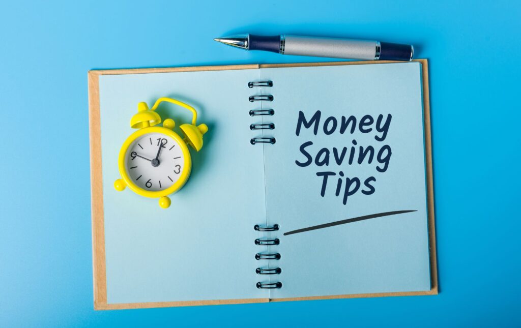 An open journal with a clock alongside "Money Saving Tips"